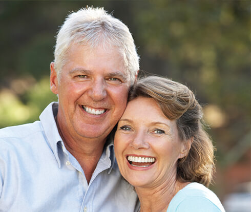 Husband and wife smiling outside