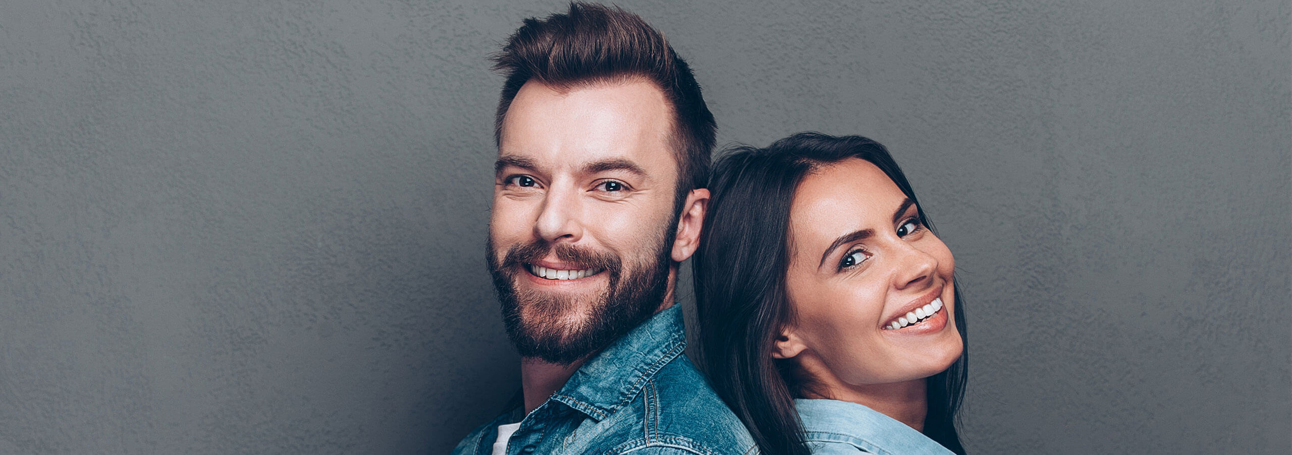 couple standing back-to-back smiling