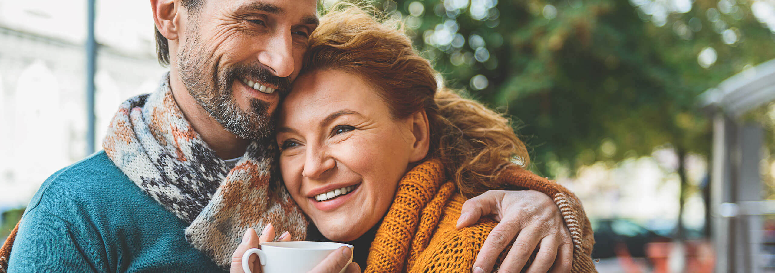 couple wearing scarves drinking coffe outside