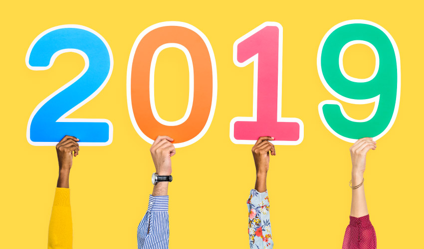 4 hands hold up multicolored 2019 numbers for our Bethea Family Dentistry year in review blog post