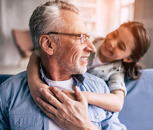 an older man getting a hug from his granddaughter