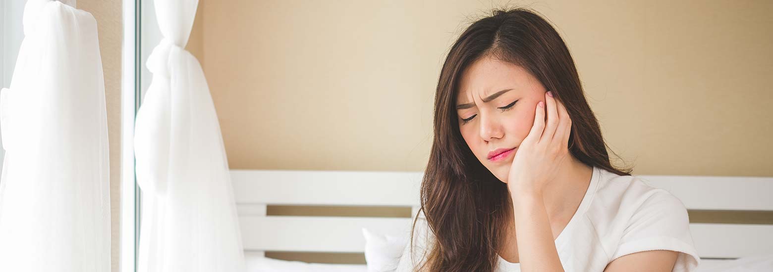 woman holding her jaw in pain