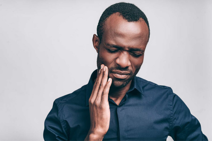 Man with his hand to his cheek due to tooth pain.