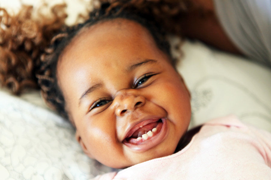 Adorable smiling black toddler just getting her baby teeth.